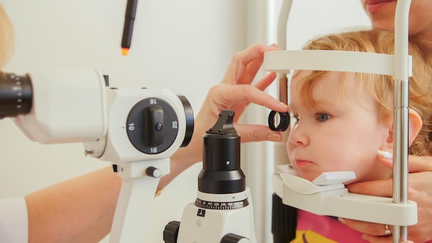 Doctor optometrist checks eyesight at little girl - child's ophthalmology, telephoto