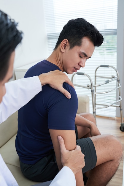 Doctor Palpating Patients Shoulder At Clinic