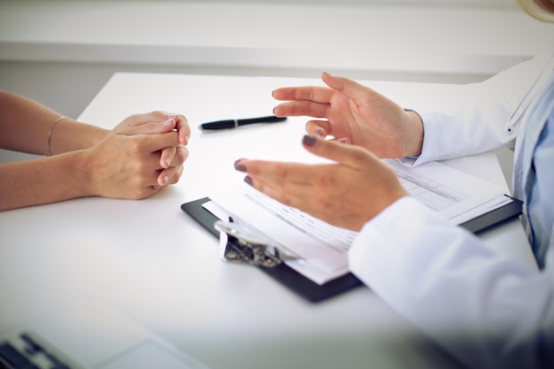 Doctor and patient are discussing something, just hands at the table.