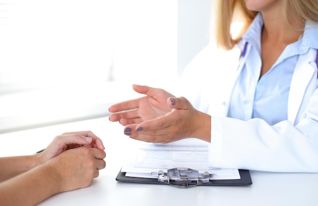 医者と患者は何かを話しているだけで、テーブルに手を置いています。