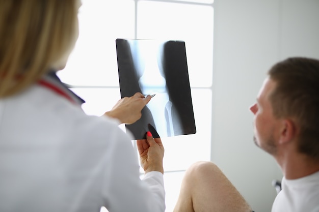 Photo doctor and the patient are looking at x ray