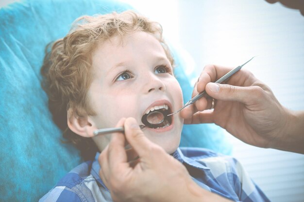 의사와 환자 아이입니다. 그의 치아를 치과 의사와 검사하는 데 소년입니다. 의학, 건강 관리 및 구강학 개념입니다.