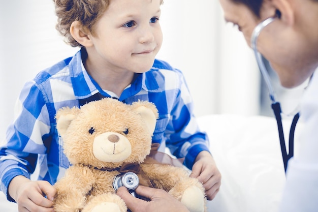 의사와 환자 아이입니다. 의사는 어린 소년을 검사합니다. 정기적인 진료소 방문. 의학 및 건강 관리 개념입니다.