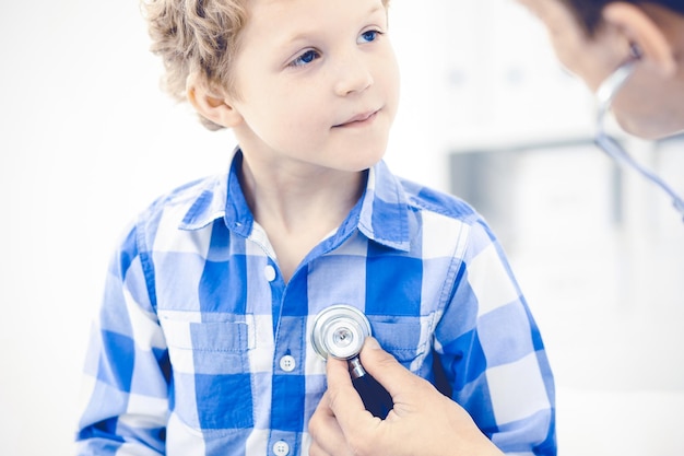 Foto dottore e bambino paziente. il medico che esamina il ragazzino. visita medica regolare in clinica. concetto di medicina e assistenza sanitaria.