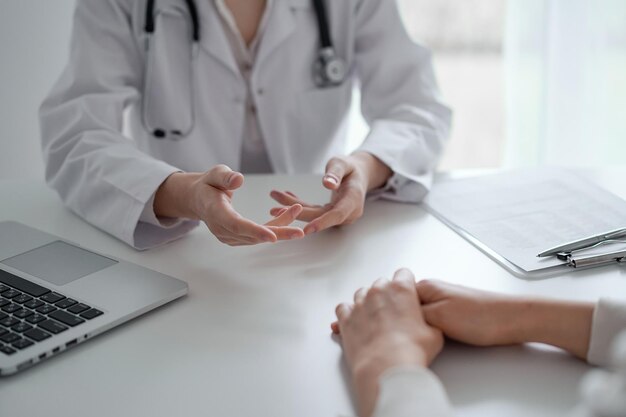 Doctor and patient discussing current health examination while sitting at the desk in clinic office, closeup. medicine concept