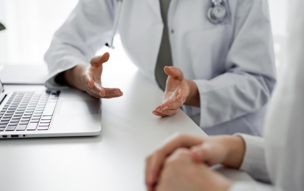 Doctor and patient discussing current health examination while sitting at the desk in clinic office, closeup. Perfect medical service and medicine concept.