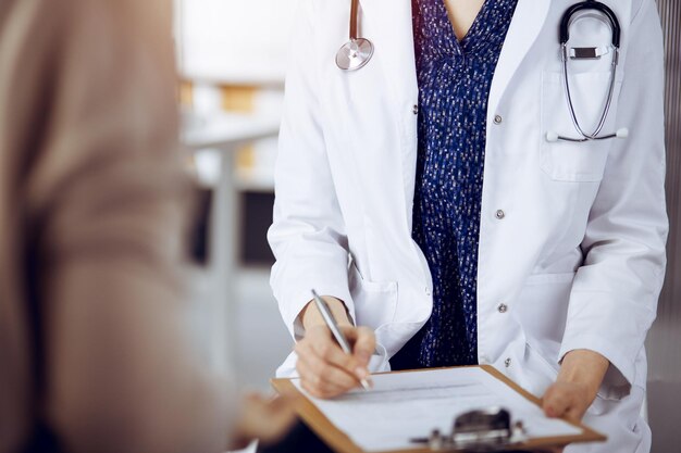 Doctor and patient discussing current health examination while sitting in sunny clinic. Medicine concept.