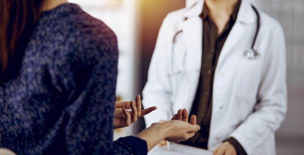 Foto medico e paziente che discutono dell'attuale esame sanitario mentre sono seduti in una clinica soleggiata concetto di medicina