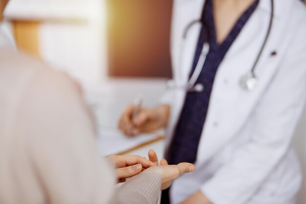 Doctor and patient discussing current health examination while sitting in sunny clinic. Perfect medical service in hospital.