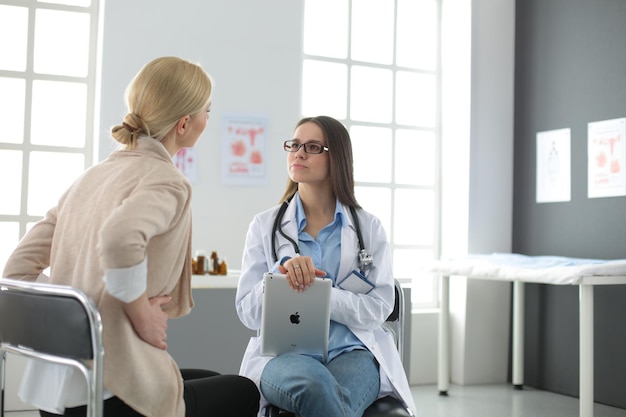 Doctor and patient discussing something while sitting at the\
table medicine and health care concept