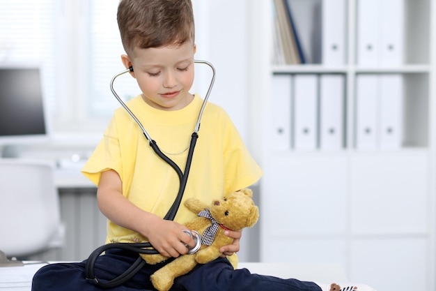 Doctor and patient in hospital Happy little boy having fun while being examined with stethoscope Healthcare and insurance concept