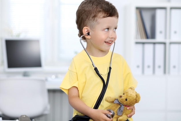 Doctor and patient in hospital Happy little boy having fun while being examined with stethoscope Healthcare and insurance concept