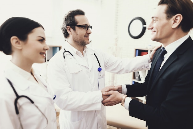 Foto doctor and patient is shakes hands in clinic.