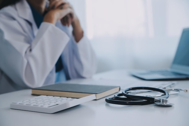 Doctor and patient sitting at the desk in clinic office The focus is on female physicians hands filling up the medication history record form close up Medicine concept