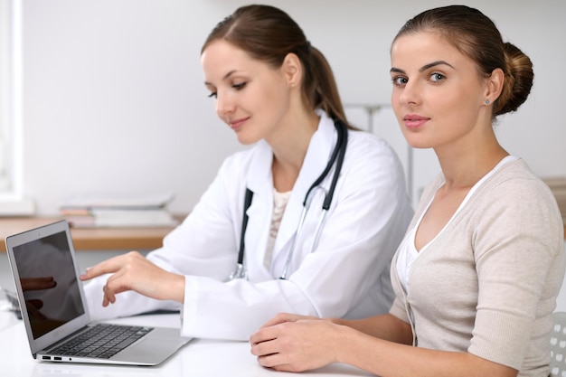 Doctor and patient sitting at the desk Physician pointing into laptop computer Medicine and health care concept