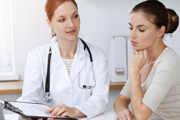 Doctor and patient sitting and discussing health examination results in sunny clinic.