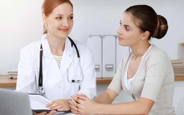 Doctor and patient sitting and discussing health examination results in sunny clinic.