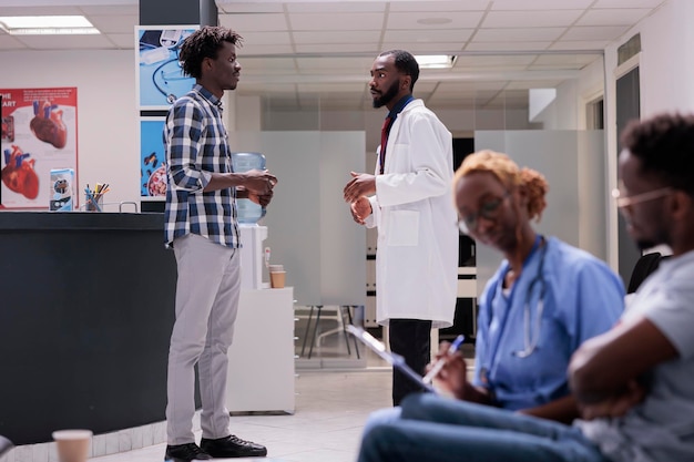 Doctor and patient talking in waiting area lobby at health center to do medical consultation and checkup visit. Treating disease diagnosis with medicine and treatment, examination in waiting room.