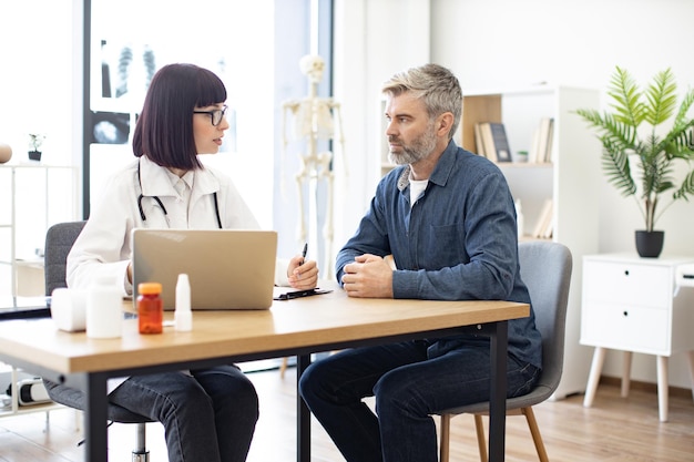 Doctor and patient watching at monitor of personal laptop