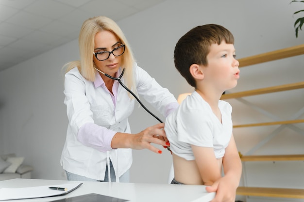 Doctor pediatrician examines child Female doctor puts a stethoscope to a child's chest and listens to the little boy's heartbeat and lungs Concept of health care and pediatric medical examination