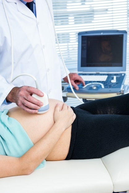 Doctor performing ultrasound on pregnant woman