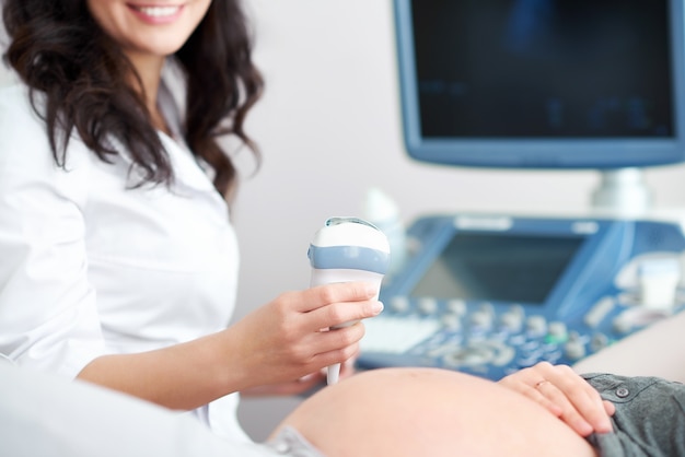 Photo doctor performing ultrasound scanning for her pregnant patient 