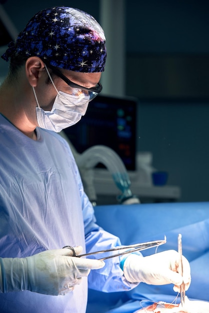 The doctor performs an operation in a dark operating room with a lamp in the background a profession