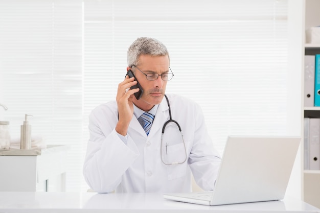 Doctor phoning and using computer 