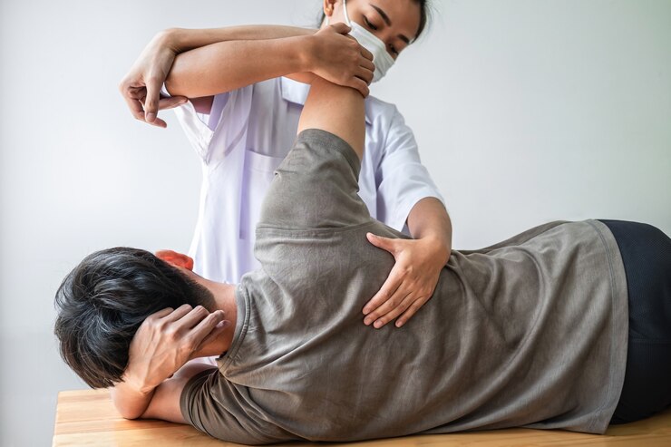 医師または理学療法士が、アスリートの男性患者の負傷した背中の治療を調べる