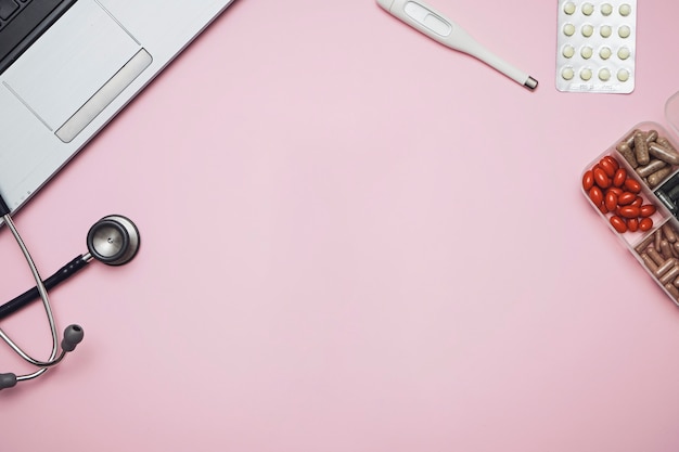 Photo doctor pink desk table with stethoscope, medicine, notebook