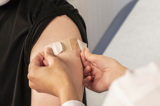 The doctor places a bandage on the patient's arm