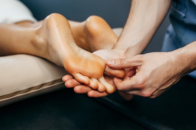 The doctor-podiatrist does an examination and massage of the\
patient\'s foot in the clinic.