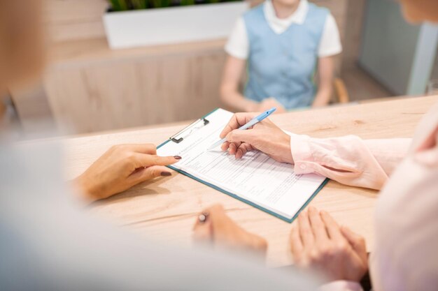 Doctor pointing her patient where to sign the form