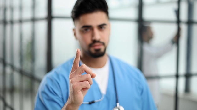 Doctor pointing up finger standing in the lobby of the hospital