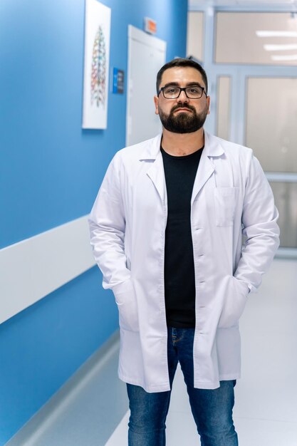 Doctor portrait on hospital corridor background. Doctor portrait in scrubs. Bearded doctor.