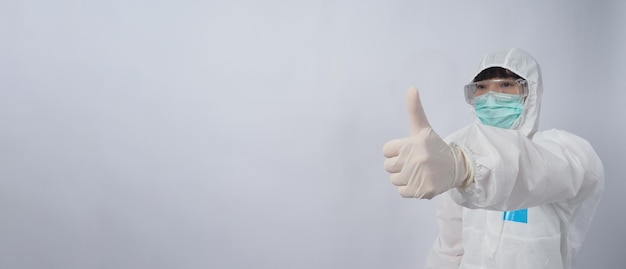 Doctor in PPE suit wearing white medical rubber gloves and clear goggles and green N95 face mask to protect pandemic Coronavirus gesture make hand sign Represent victory win over virus Isolated