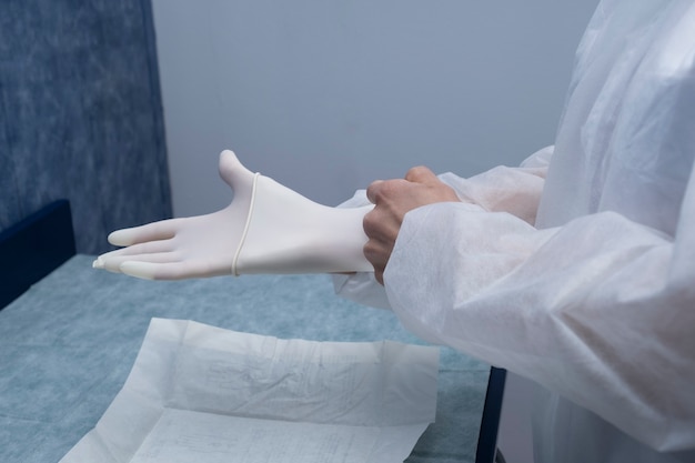 A doctor prepares to attend to a patient.
The woman prepares (protective suits,googles,gloves and masks) all the necessary protections to protect itself from covid-19