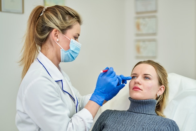 Doctor preparing female patient for cosmetic surgery in clinic