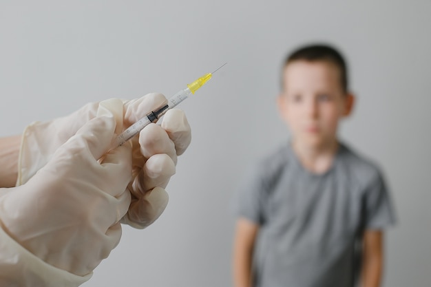 写真 子供の予防接種に注射器で予防接種注射を準備する医師