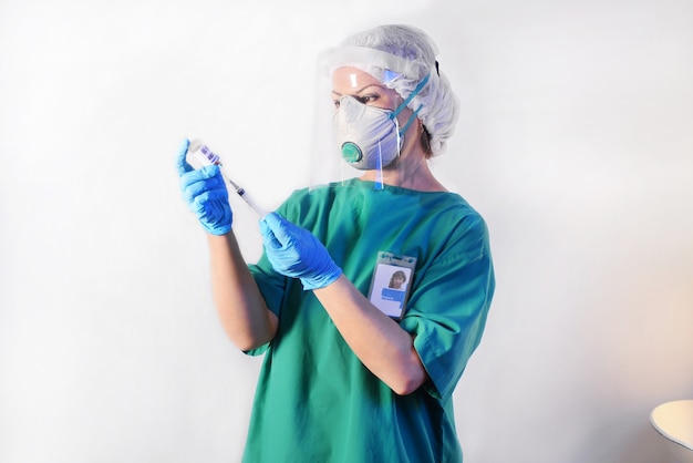 Doctor in protective mask, medical latex gloves draws a medicinal fluid into the syringe