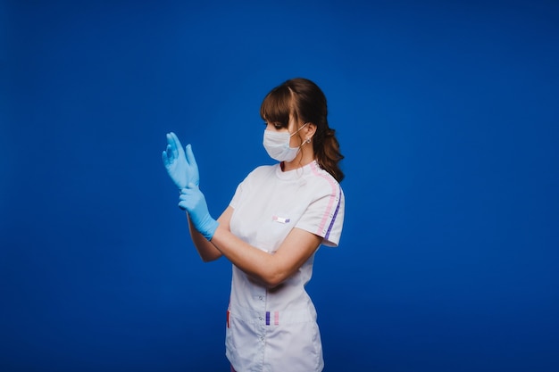 врач в защитной маске и резиновых перчатках на синем фоне