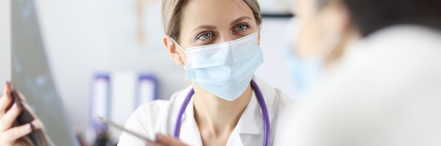 Doctor in protective mask showing patient x ray