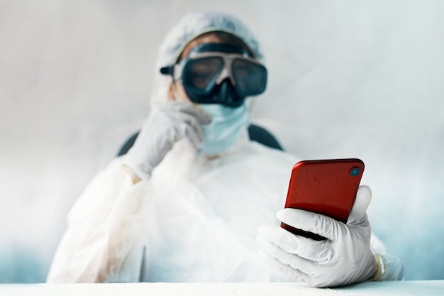 Photo doctor in the protective suit with smartphone