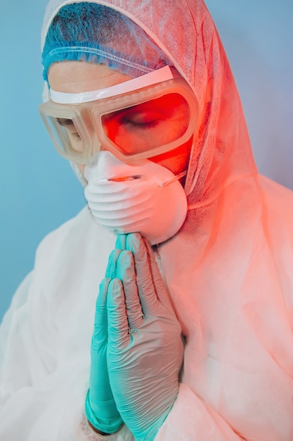 Doctor in protective uniform, reperitor, glasses, gloves. man prays