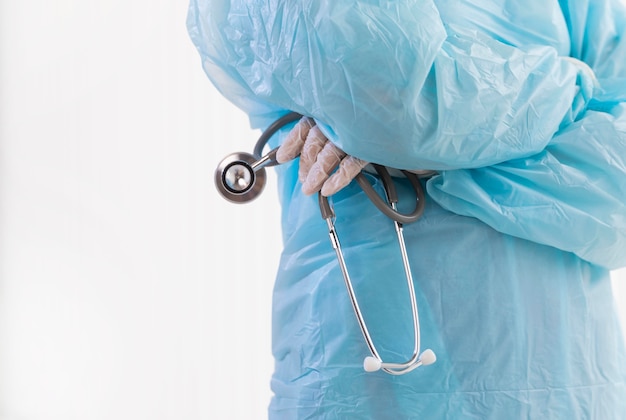 Medico in abbigliamento protettivo che tiene un primo piano dello stetoscopio