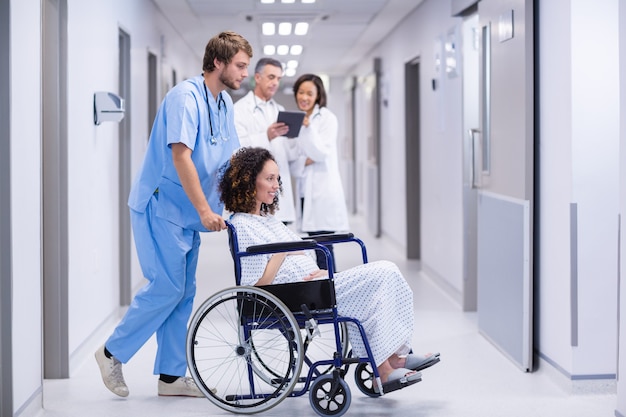 Doctor pushing a pregnant woman on wheelchair