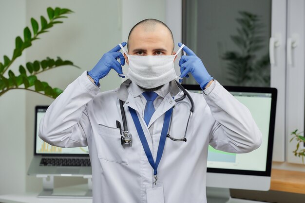 A doctor putting on a face mask in his office.