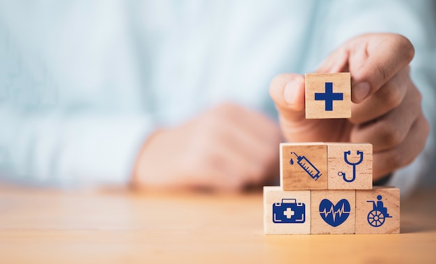 Doctor putting healthcares icon which print screen on stacking wooden cube for health medical insurance concept