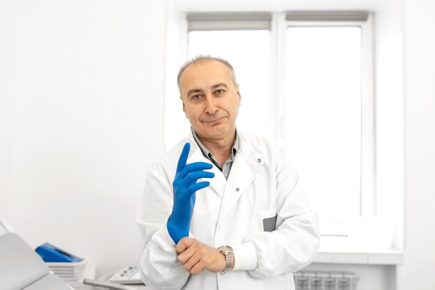 Photo doctor putting on medical gloves before examining a patient