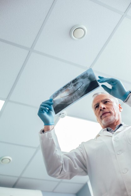 Doctor putting orthopantomogram to the light and looking attentively at it